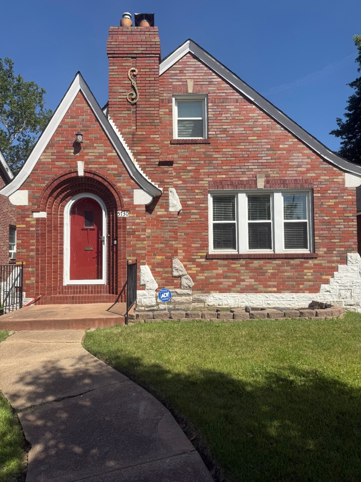 Front of 5730 Park Lane — brick Tudor-style home with arched red door